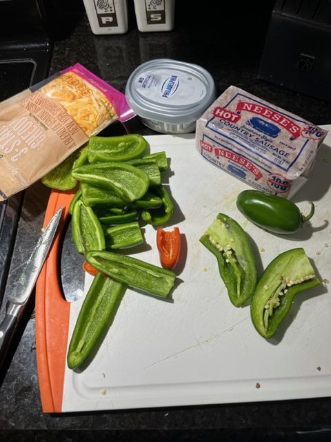 Ingredients for smoked jalapeno peppers, including peppers, shredded cheese, cream cheese and sausage.