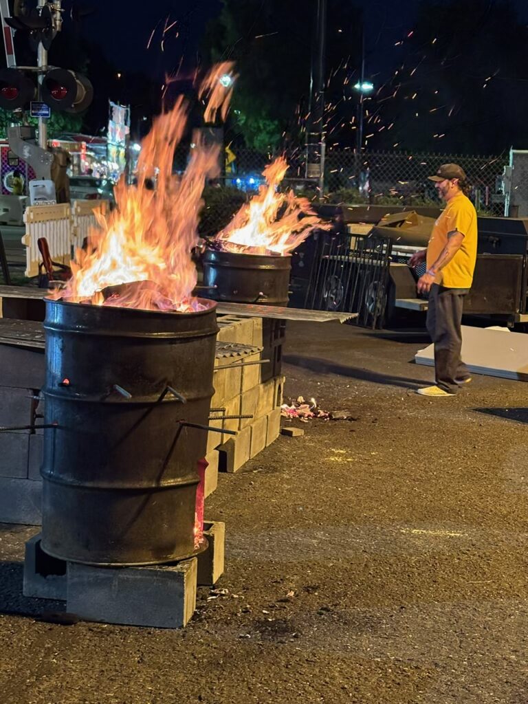 Burn barrels light up the night in uptown Charlotte during the 2025 Carolina BBQ Festival.